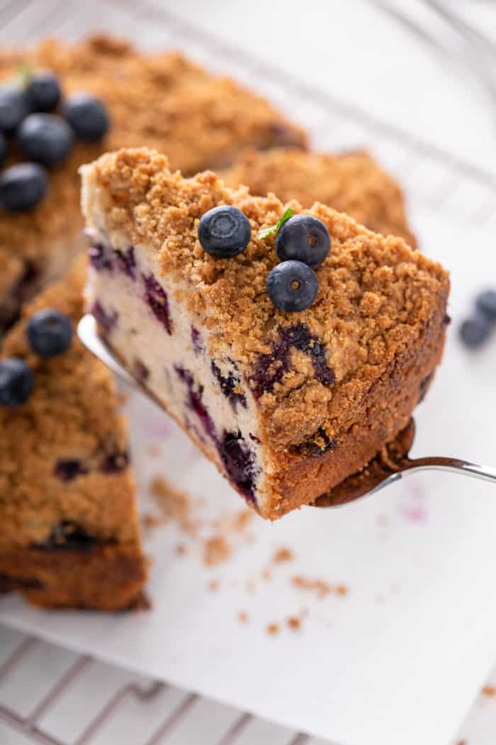 Slice of blueberry buckle being lifted up with a cake server.