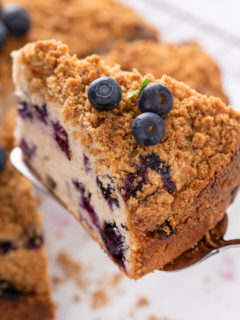 Cake server lifting up a slice of blueberry buckle.