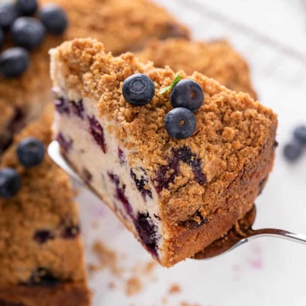Cake server lifting up a slice of blueberry buckle.