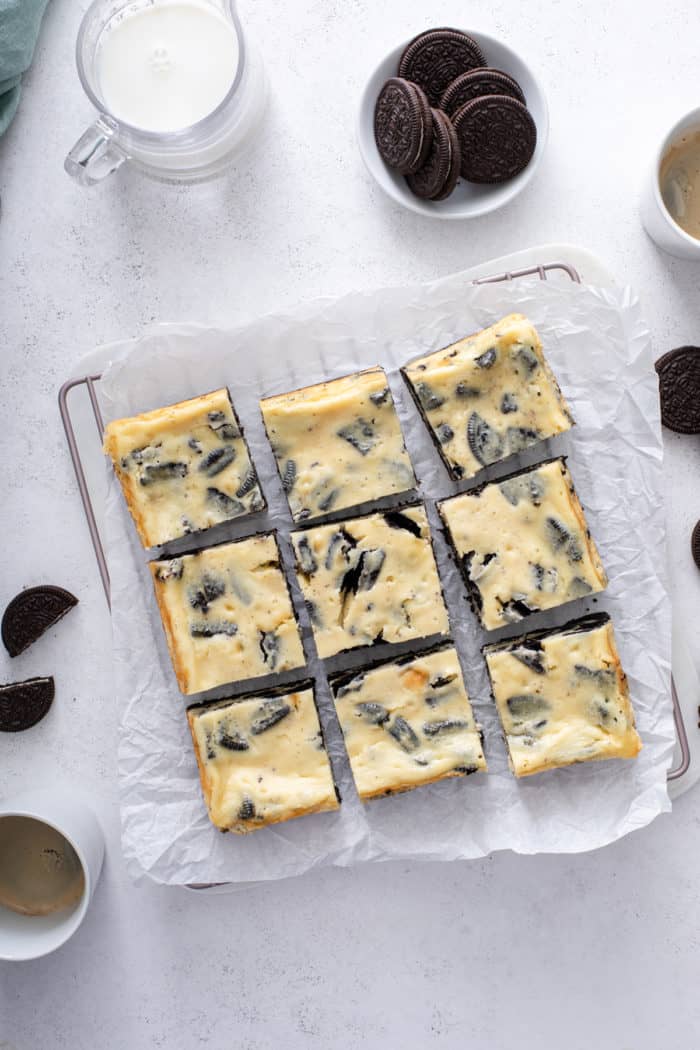 Overhead view of baked, cooled, and sliced oreo cheesecake bars on a piece of parchment paper.
