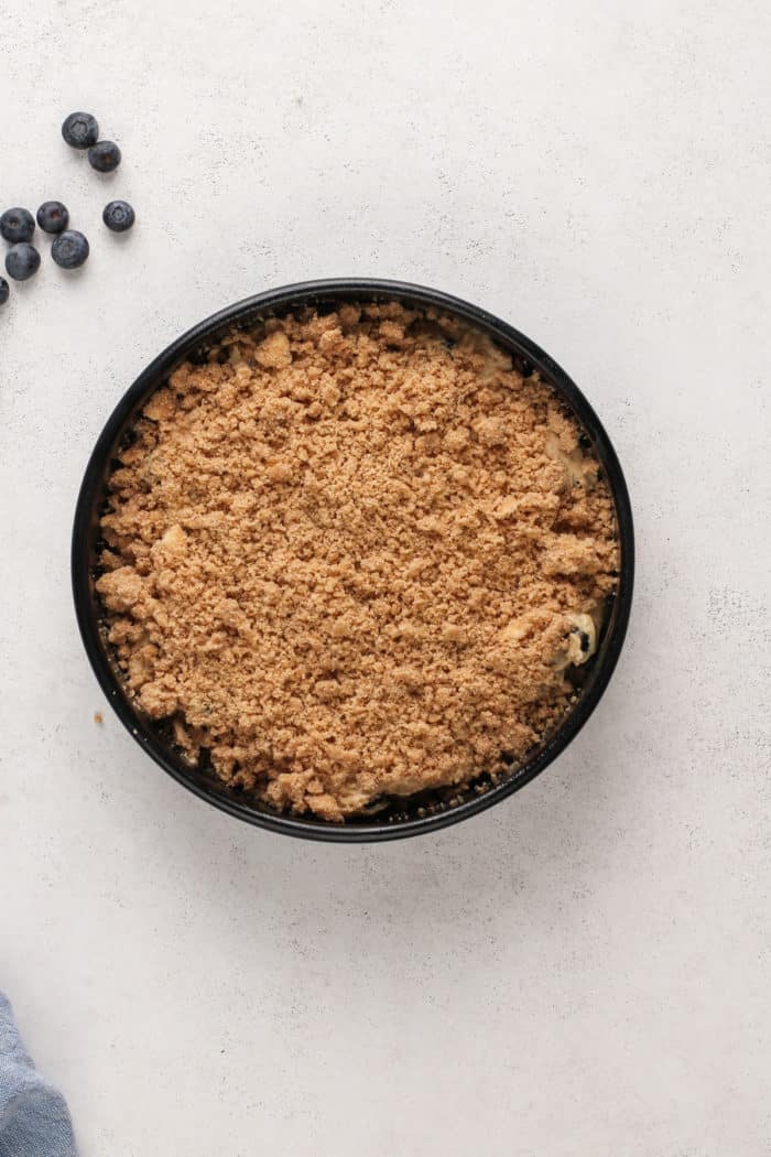 Assembled blueberry buckle in a cake pan, ready to go in the oven.