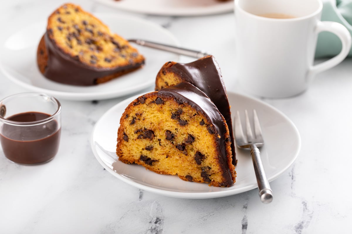 Two white plates holding slices of chocolate chip bundt cake next to a cup of coffee.