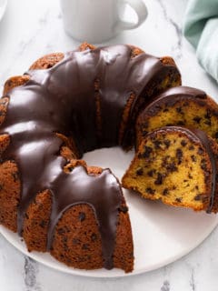 White cake plate holding a sliced chocolate chip bundt cake.