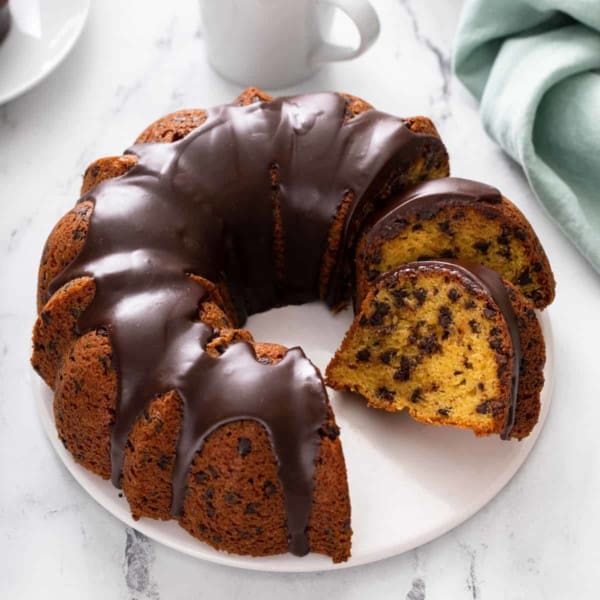 White cake plate holding a sliced chocolate chip bundt cake.