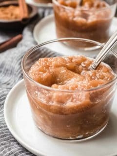 Glass dish of slow cooker applesauce with a spoon in it