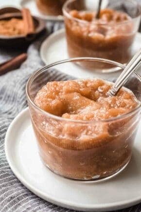 Glass dish of slow cooker applesauce with a spoon in it