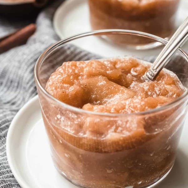 Glass dish of slow cooker applesauce with a spoon in it