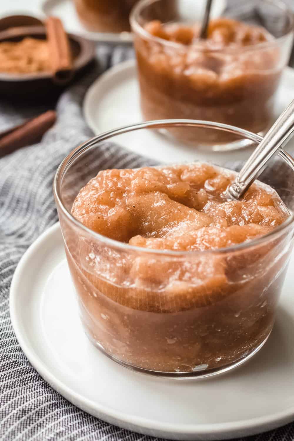 Glass dish of slow cooker applesauce with a spoon in it