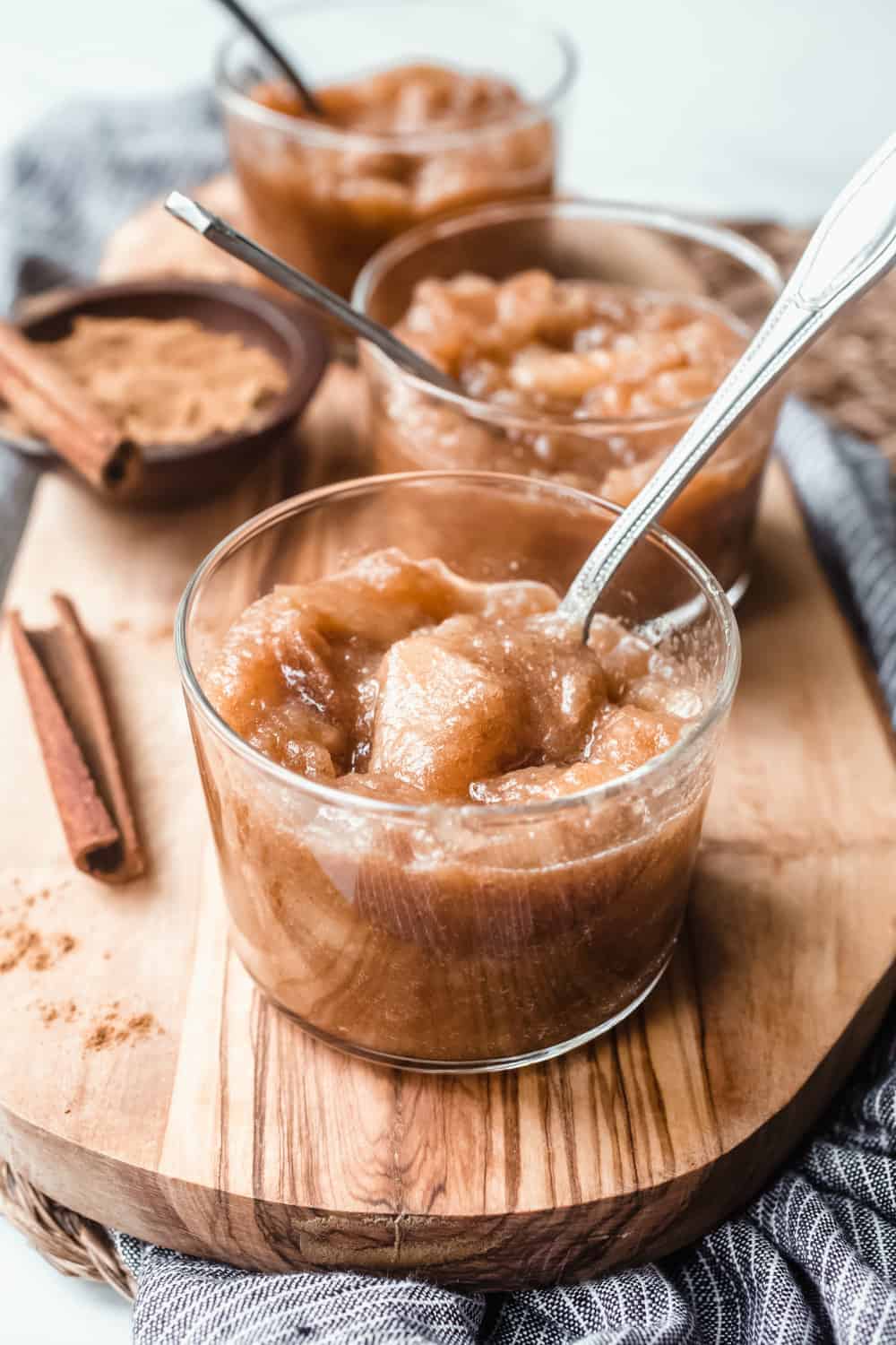 Glass bowl of homemade crockpot applesauce with additional bowls in the background