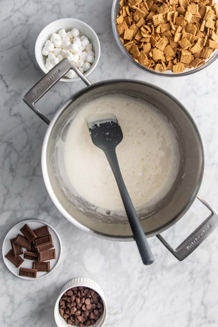 Marshmallows and butter melted together in a metal saucepan to make golden grahams smores.