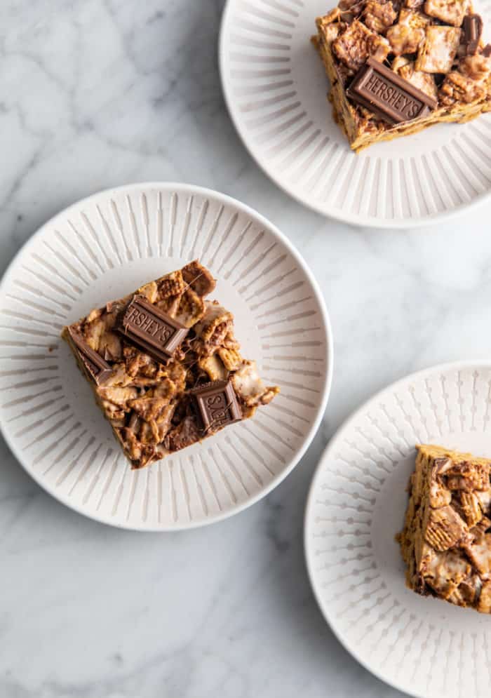 Three white plates, each holding a golden graham s'mores.