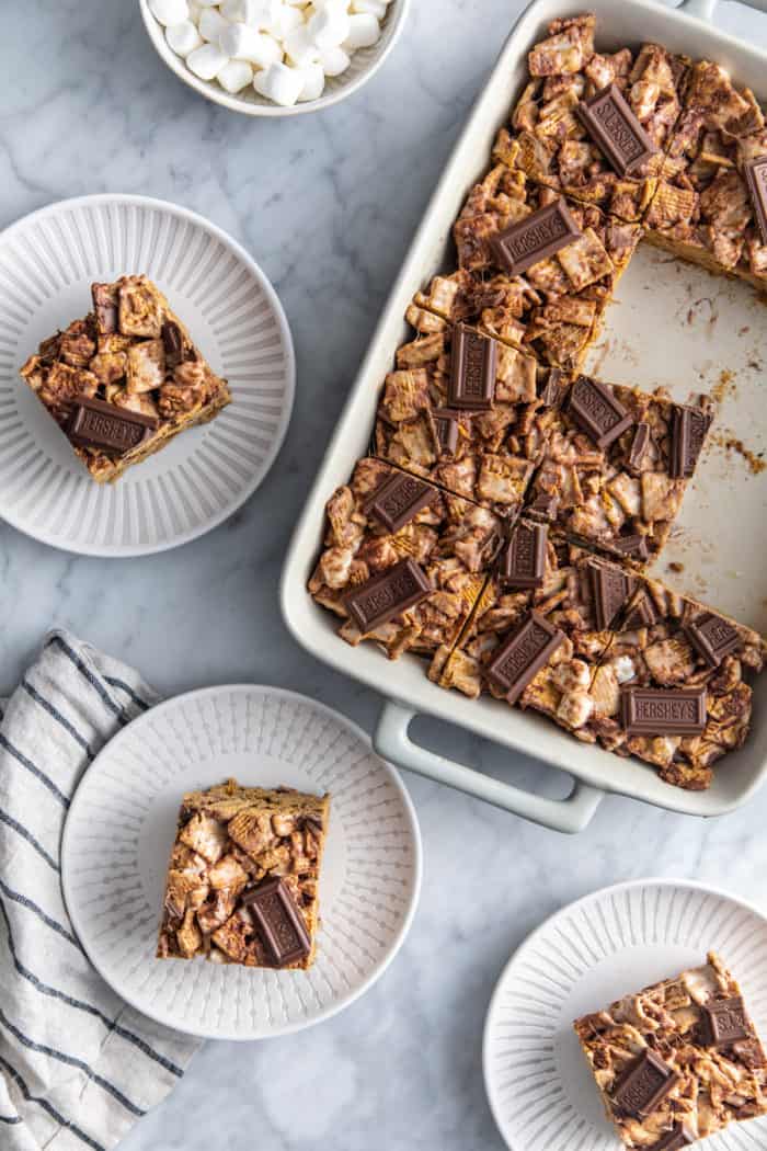 Overhead view of a pan of golden graham s'mores surrounded by plates of the s'mores bars.