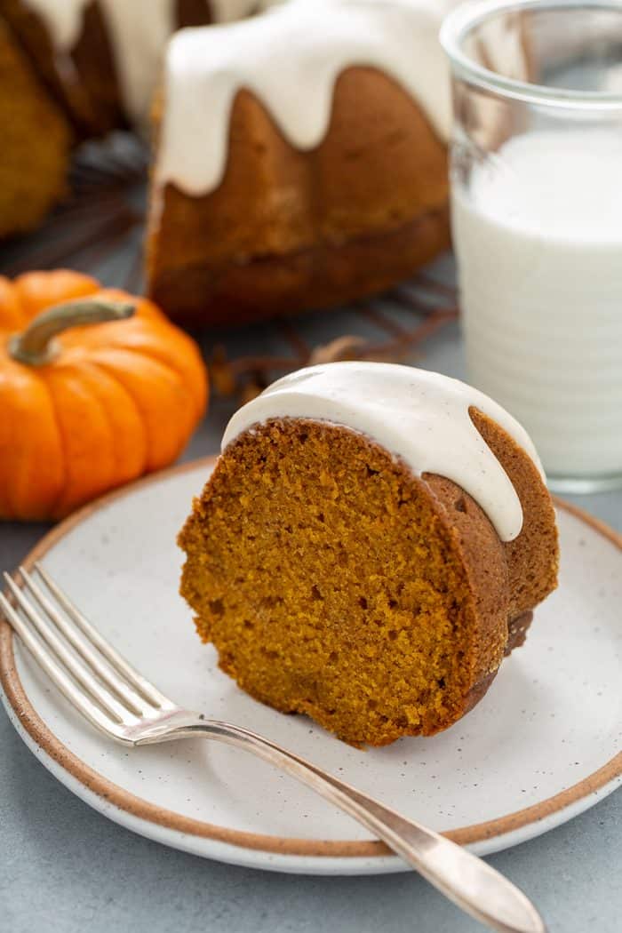 Slice of pumpkin bundt cake next to a fork on a white plate