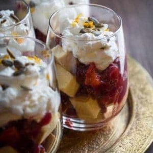 Four glass cups of cranberry trifle on a gold plate