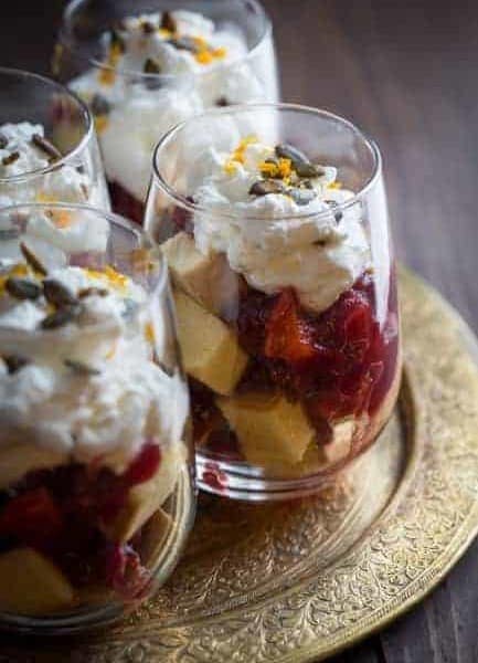 Four glass cups of cranberry trifle on a gold plate