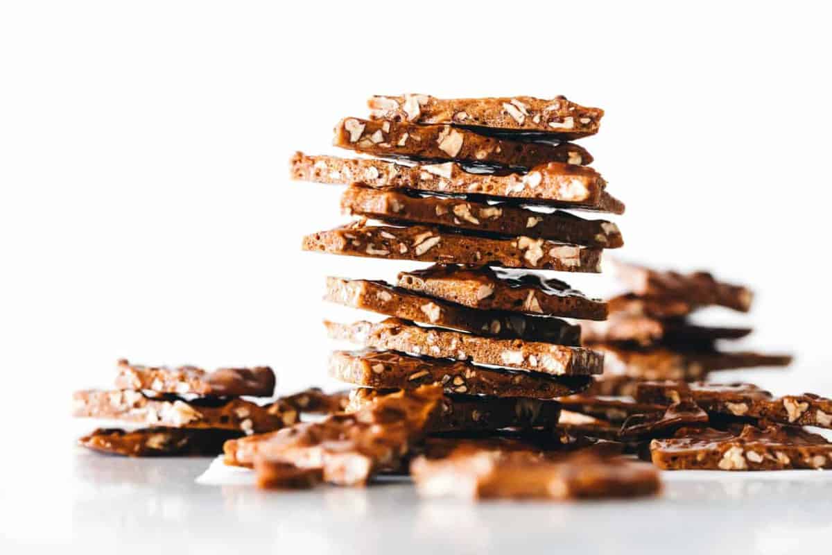 Stacked pieces of pecan brittle in front of a white background