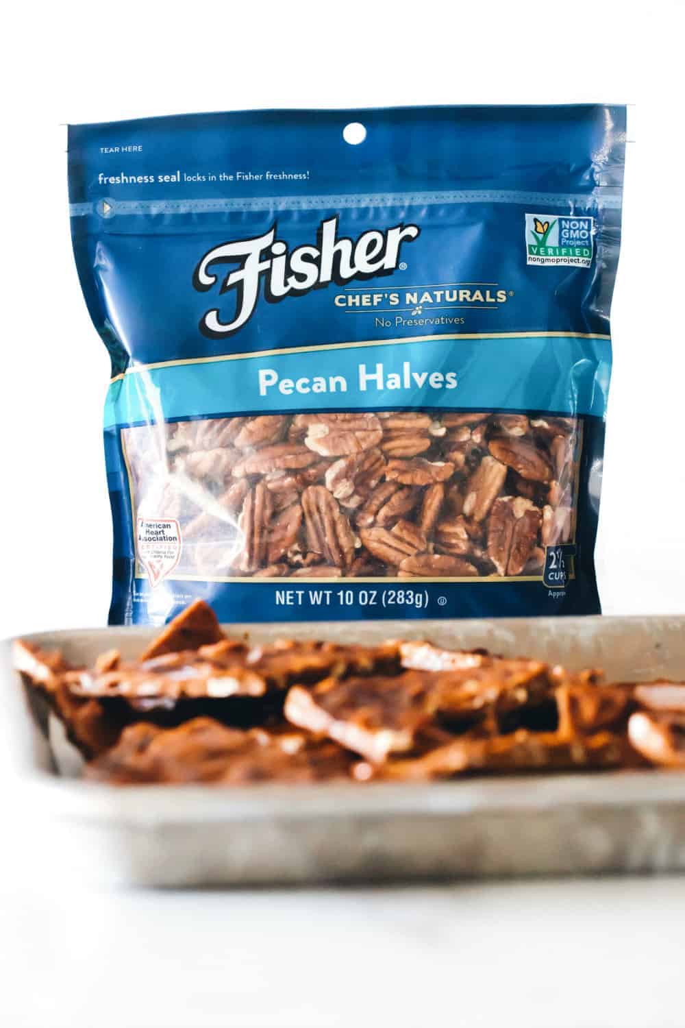 Pecan brittle on a sheet tray in front of a bag of pecan halves