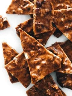 Shards of pecan brittle on a piece of parchment paper
