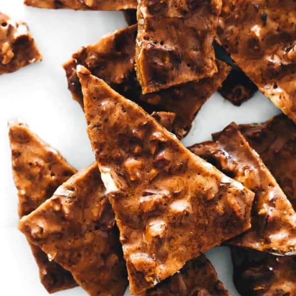 Shards of pecan brittle on a piece of parchment paper