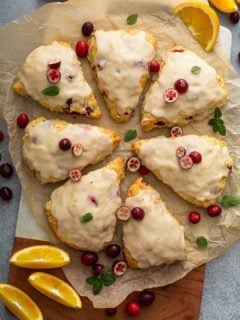 8 glazed cranberry orange scones arranged in a circle on a piece of parchment