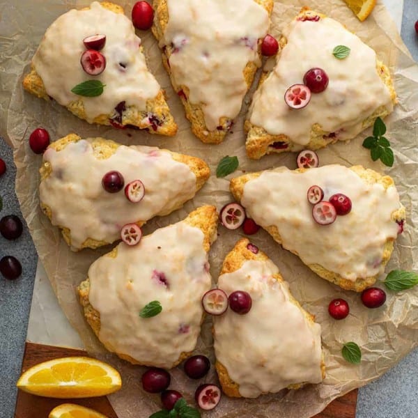 8 glazed cranberry orange scones arranged in a circle on a piece of parchment