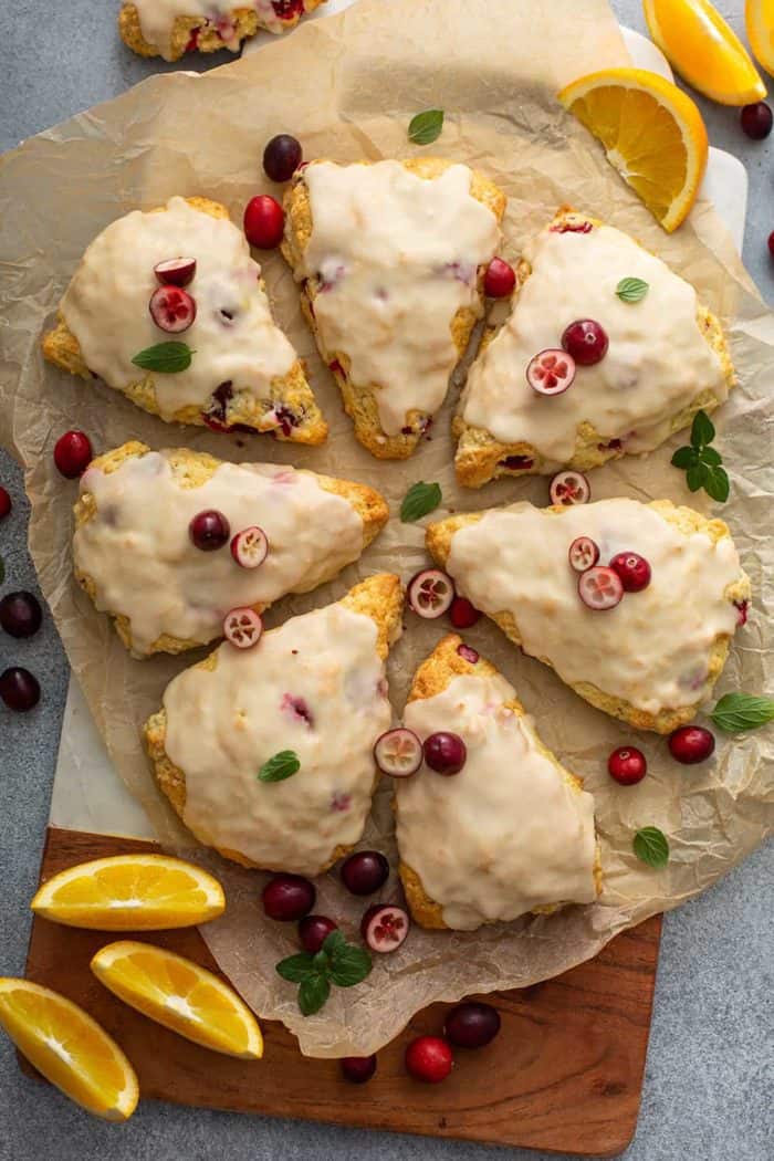 8 glazed cranberry orange scones arranged in a circle on a piece of parchment