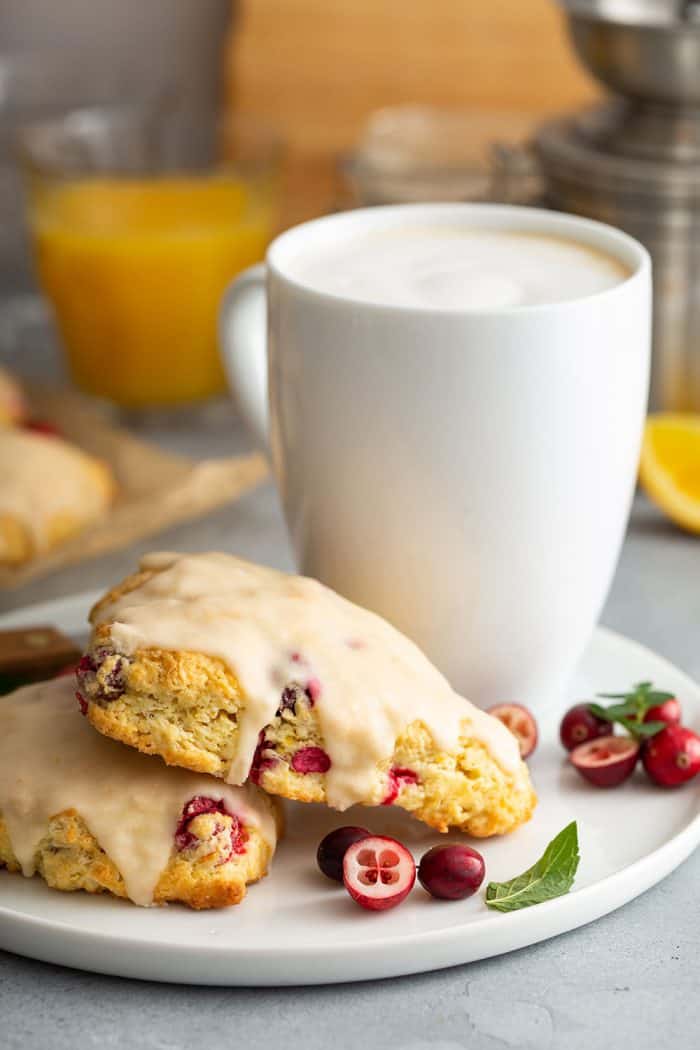 Cranberry orange scones on a white plate next to a mug of coffee