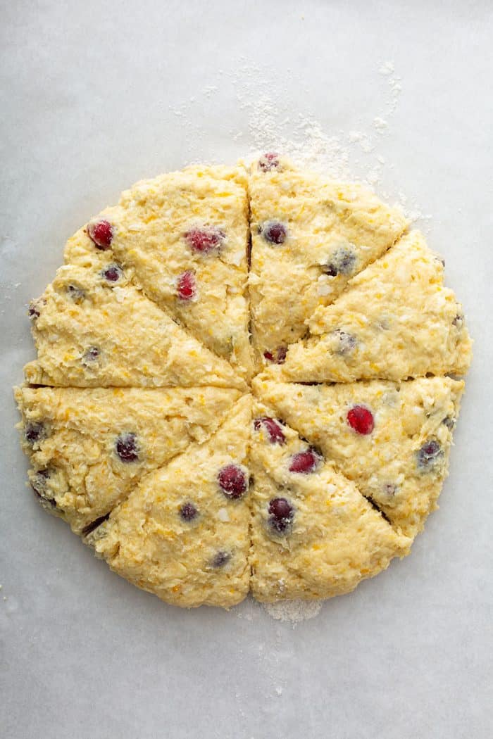 Cranberry scone dough shaped into a circle and cut into 8 pieces on a floured surface