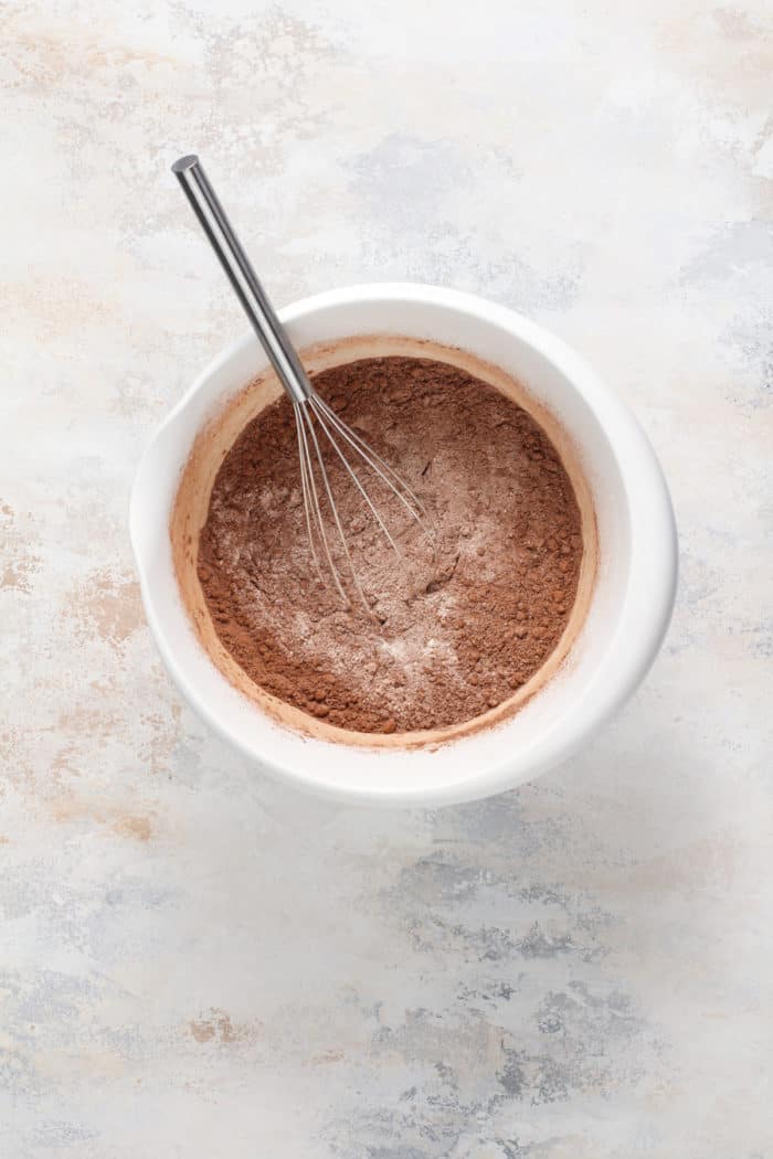 Dry ingredients for chocolate bread being whisked together in a white bowl.