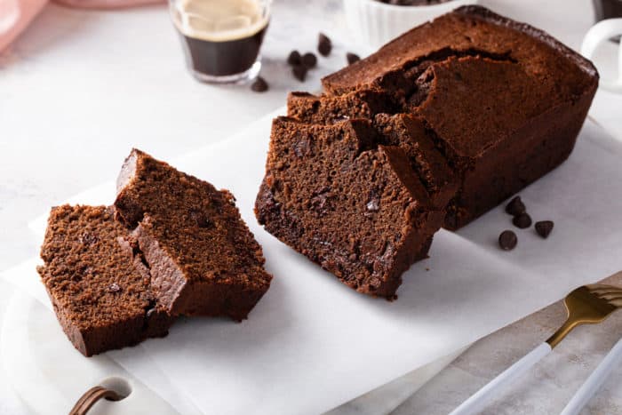 Sliced loaf of chocolate bread set on a white cutting board.