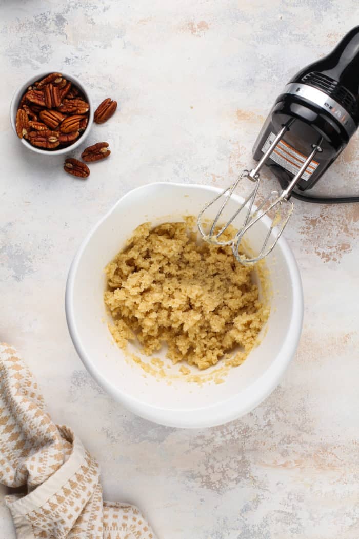 Butter and sugar creamed together in a white mixing bowl.