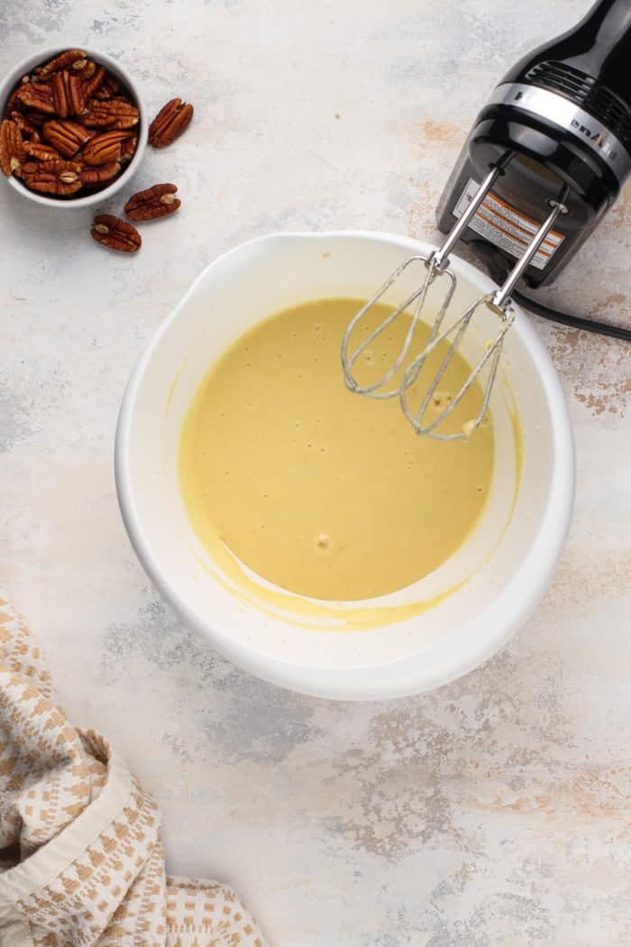 Wet ingredients for banana bars in a white mixing bowl.