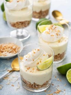 Assembled key lime cheesecakes topped with whipped cream and lime wedges