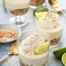 Assembled key lime cheesecakes topped with whipped cream and lime wedges