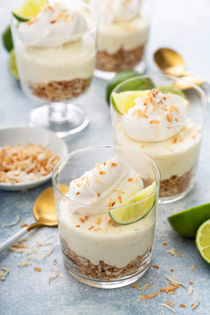 Assembled key lime cheesecakes topped with whipped cream and lime wedges
