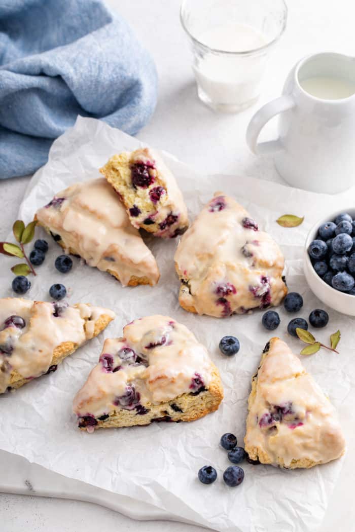 Glazed blueberry scones arranged on a piece of parchment paper.