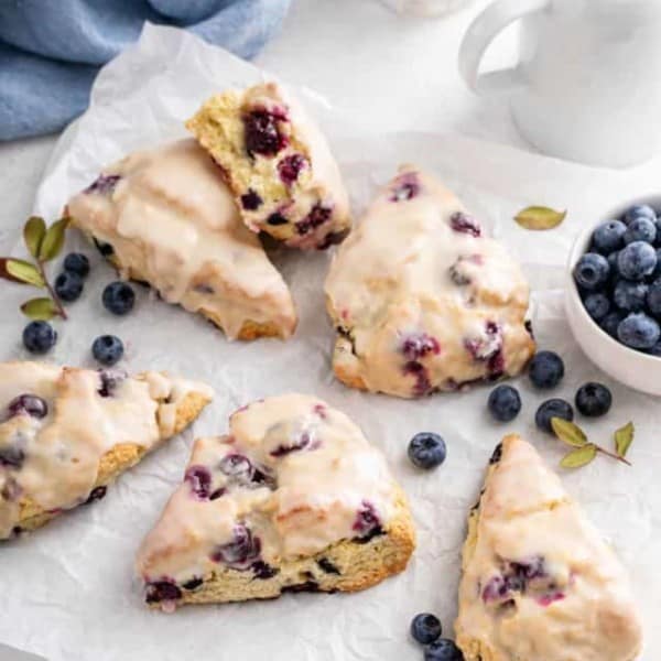 Glazed blueberry scones arranged on a piece of parchment paper.