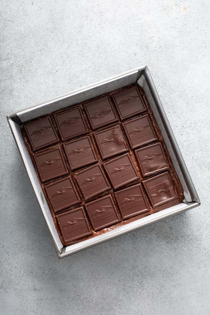 Ghirardelli sea salt caramel chocolates arranged on top of brownie batter in a metal baking pan