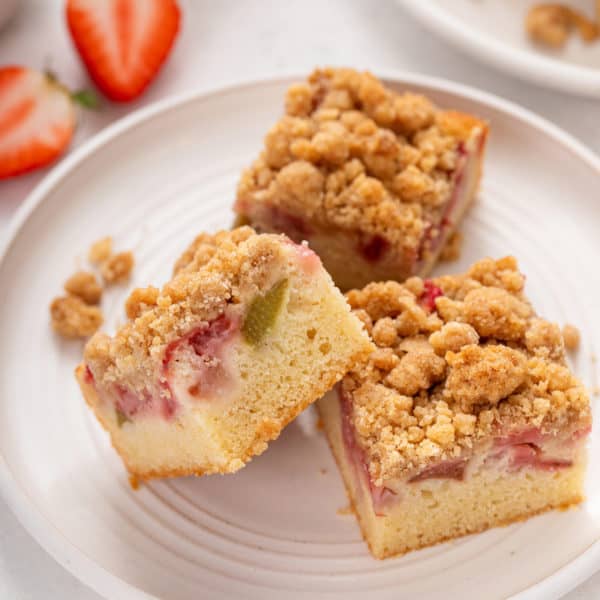 Three slices of strawberry rhubarb crumb cake on a white plate.
