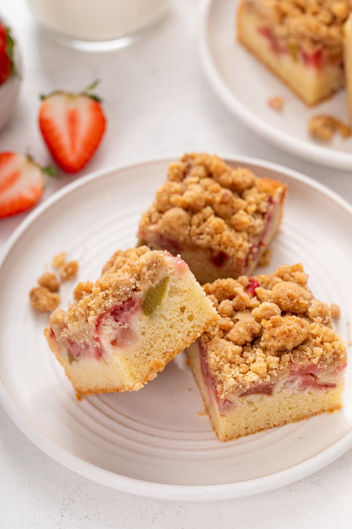 Three slices of strawberry rhubarb cake arranged on a white plate.