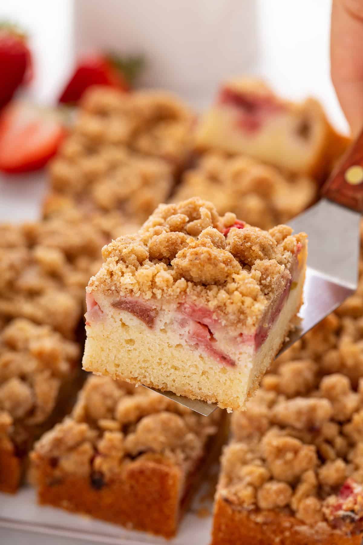 Slice of strawberry rhubarb cake being lifted up with a cake server.
