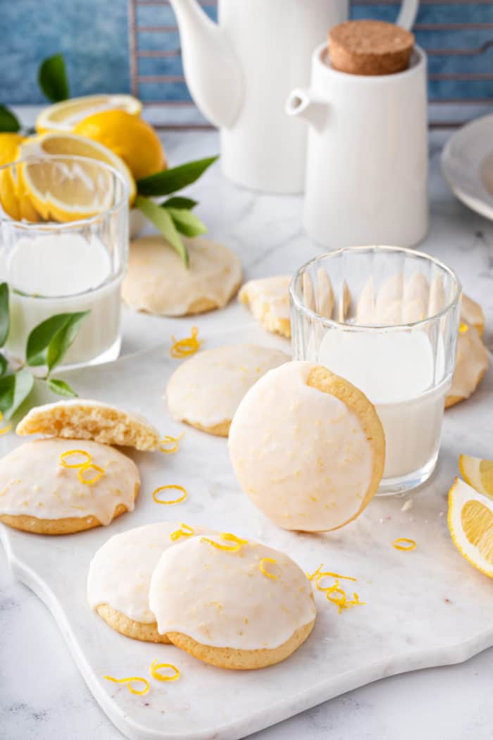 Lemon ricotta cookies and a glass of milk arranged on a marble board.