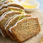 Close up of a sliced loaf of lemon zucchini bread on a piece of parchment paper