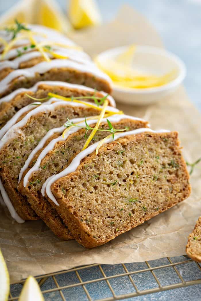 Close up of a sliced loaf of lemon zucchini bread on a piece of parchment paper