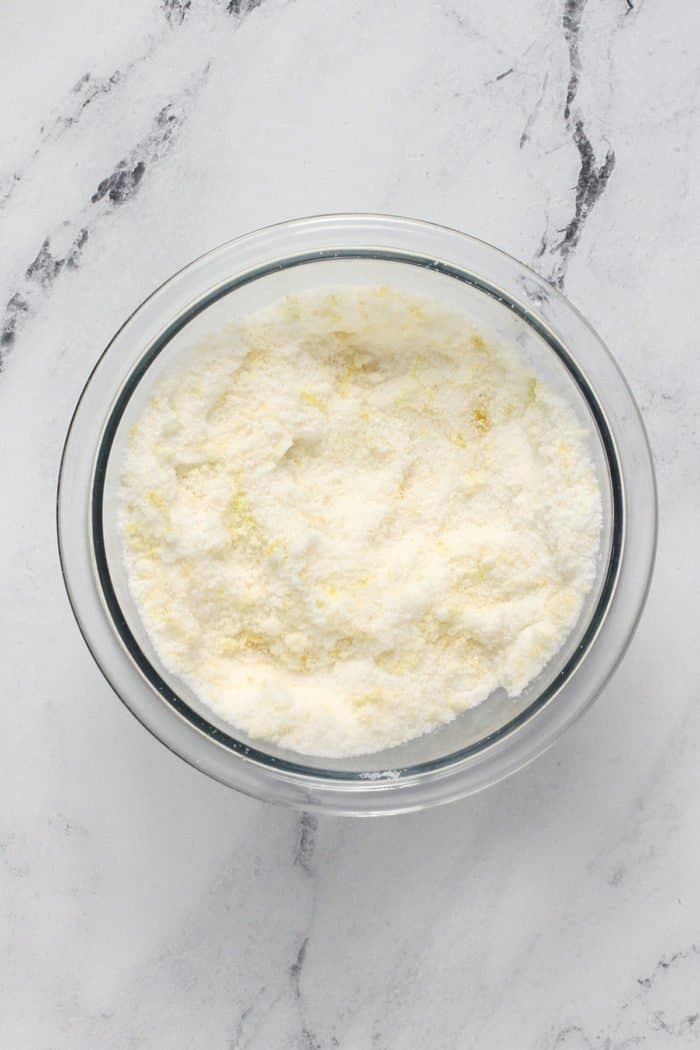 Lemon zest and sugar combined in a glass bowl.
