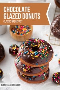 Three sprinkle-topped chocolate glazed donuts stacked on a piece of parchment paper, with more donuts and sprinkles in the background. Text overlay includes recipe name.