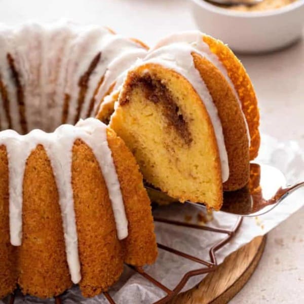 Cake server lifting up a slice of honey bun cake from the whole cake.