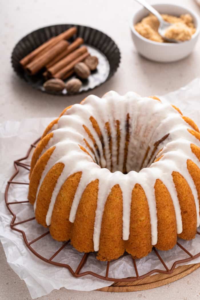 Glazed honey bun cake set on a wire rack, with whole spices visible in the background.