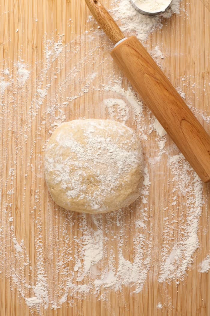 Kneaded dough for chocolate glazed donuts on a wooden surface, ready to be rolled out.