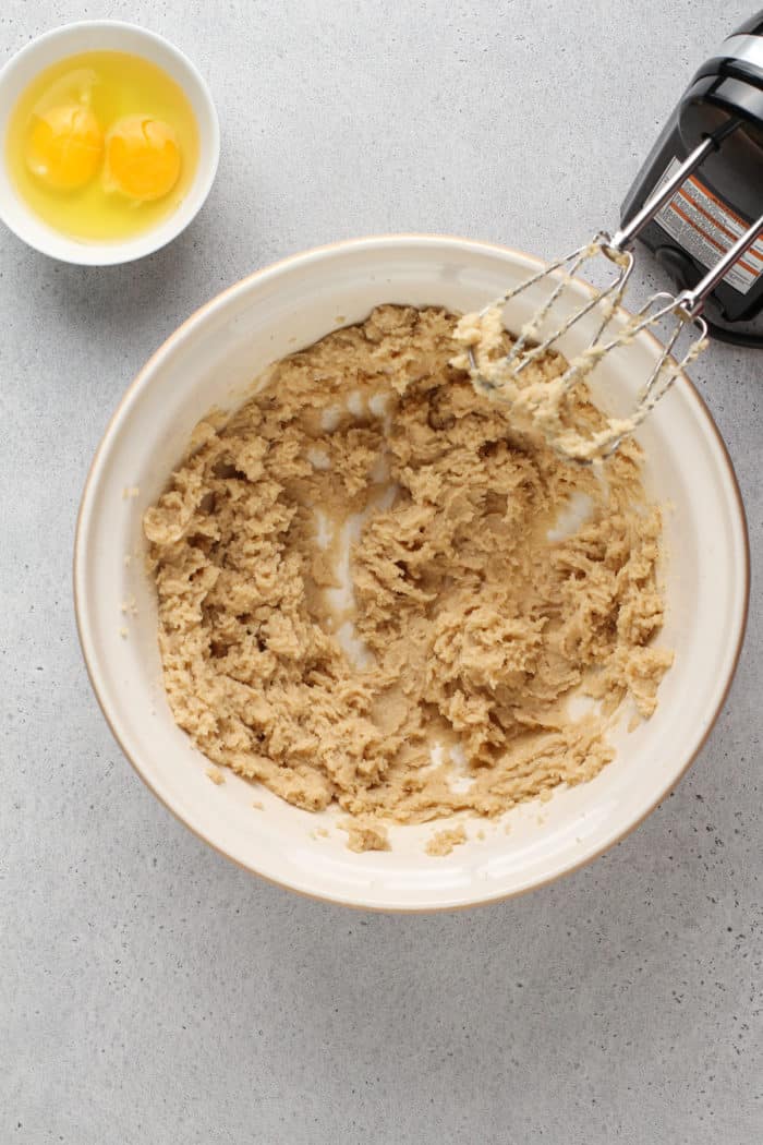 Butter and sugar creamed together in a ceramic mixing bowl.